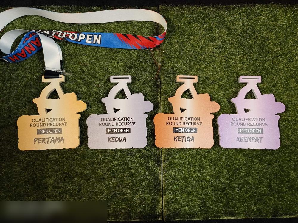EMPAT medal Batu Open (memanah, Qualification Round Recurve Men Open) menunjukkan empat warna untuk empat kedudukan: PERTAMA (emas), KEDUA (perak), KETIGA (oren/gangsa) dan KEEMPAT (ungu muda). Bentuk