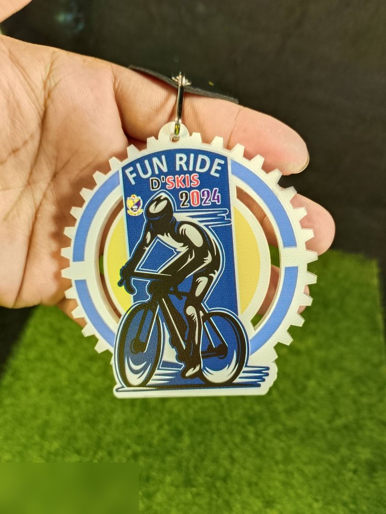 Medal Fun Ride D'SKIS 2024. Bentuk custom seperti GEAR BASIKAL bergerigi, warna putih krim dgn pelumba basikal biru dan bulatan kuning. Digantung dengan tab kulit hitam. Contoh potongan bentuk gear ya