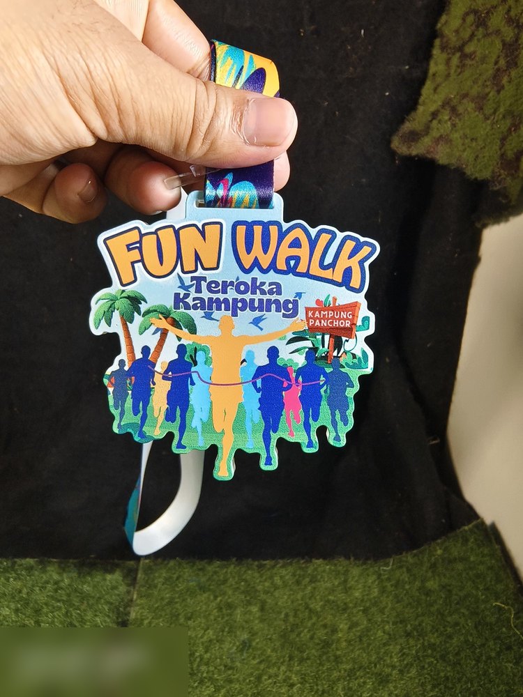 Medal Fun Walk 'Teroka Kampung' Kampung Panchor. Bentuk custom, latar biru muda dgn pokok kelapa, sekumpulan peserta berpimpin tangan dan sepanduk merah. Lanyard biru-kuning. Contoh medal acara komuni