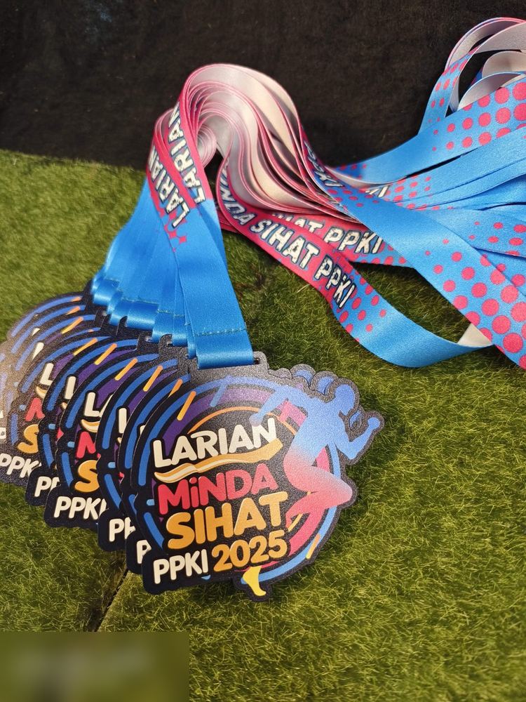 Medal Larian Minda Sihat PPKI 2025 — larian sekolah program pendidikan khas. Bentuk custom bulat bergerigi, warna gelap dengan gradasi biru-ungu-merah jambu neon dan silhouette pelari. Lanyard dua war