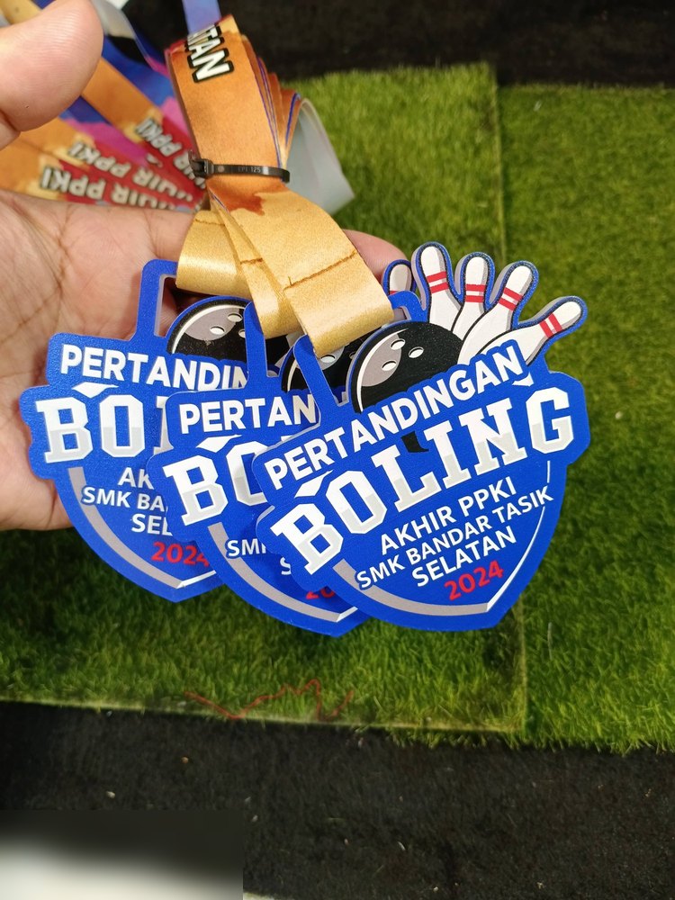 Medal Pertandingan Boling Akhir PPKI SMK Bandar Tasik Selatan 2024. Bentuk custom dgn pin bowling di sudut kanan atas, latar BIRU terang dgn teks putih tebal. Lanyard emas. Gambar tunjuk beberapa kepi