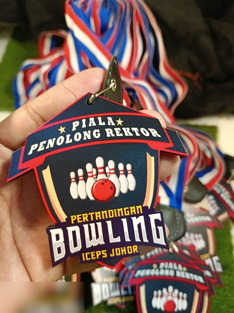 Medal Piala Penolong Rektor ICEPS Johor, Pertandingan Bowling. Bentuk perisai dgn bingkai merah, latar biru navy, pin bowling putih dan bola merah timbul, bintang emas. Lanyard jalur merah-putih-biru.
