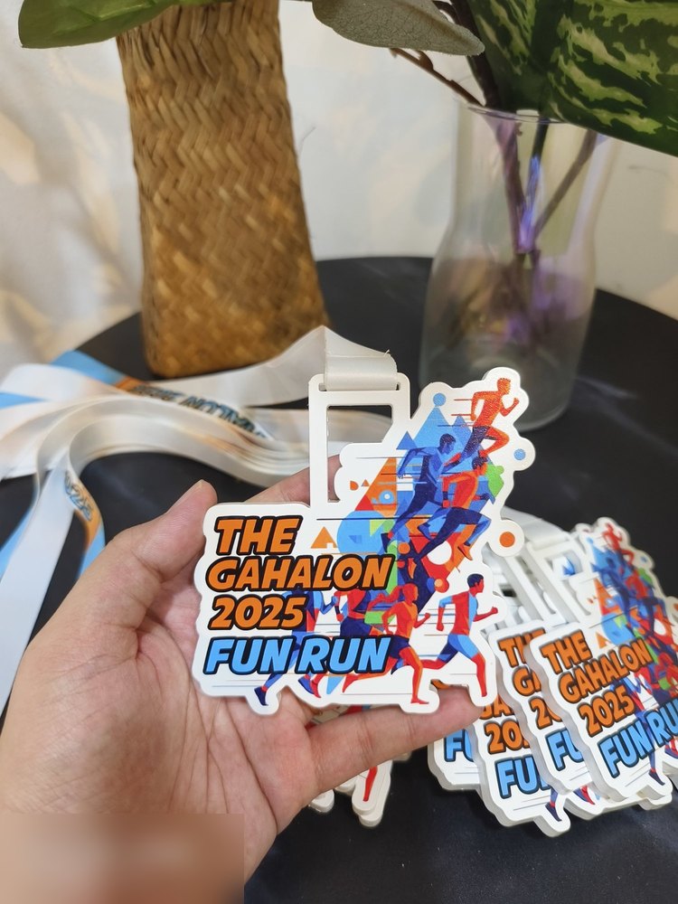 Medal The Gahalon 2025 FUN RUN — versi larian (berbeza dgn medal Gahalon obstacle yang perak). Bentuk custom, latar putih dgn kumpulan pelari warna biru, oren dan merah bergaya geometri. Lanyard putih
