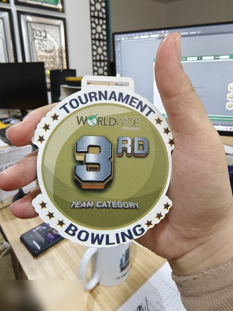 Medal Worldwide Tournament Bowling, kategori pasukan tempat KETIGA. Bentuk bulat bergerigi dgn bintang di tepi, latar hijau zaitun dgn angka '3RD' besar bergaya logam. Contoh medal kedudukan untuk kat